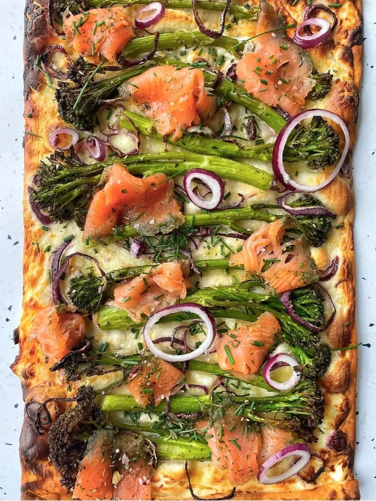 Flamkuchen met bimi en gerookte zalm, geserveerd met rode ui en bieslook